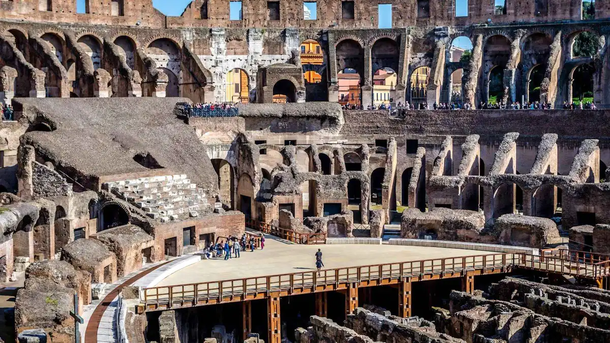Visitors on the walkway above the Colosseum hypogeum with the Roman Forum beyond on a Rome underground tour